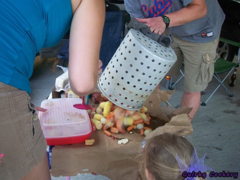 Shrimp, corn, carrots, garlic being dumped onto torn up bags and beer boxes