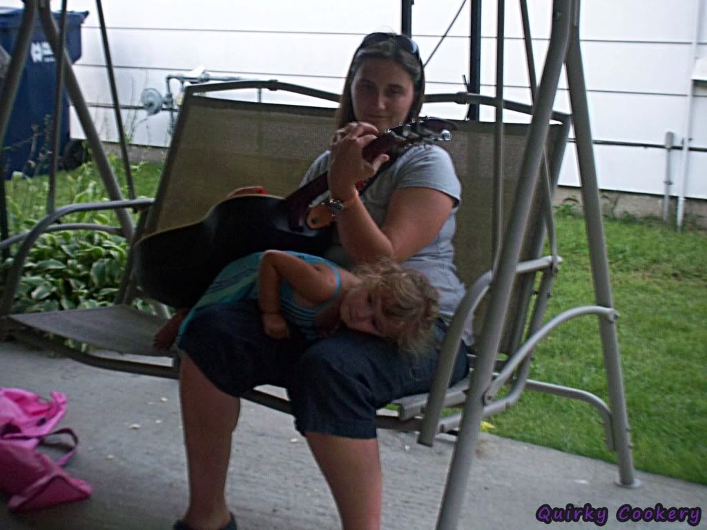 Little girl climbing onto her mom's lap while she's playing the guitar after a great party