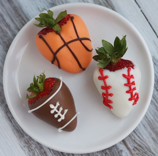 Wiltons chocolate covered strawberries painted to look like a basketball, baseball, and football with icing