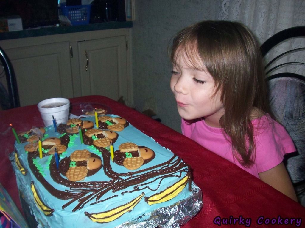 Young child blowing out candles on a monkey birthday cake