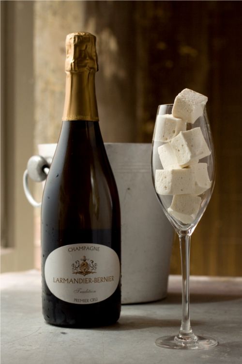 Leftover champagne to make homemade flavored marshmallows. Larmandier berner is the bottle of champagne shown in the picture next to a bucket and champagne glass filled with marshmallow squares. 