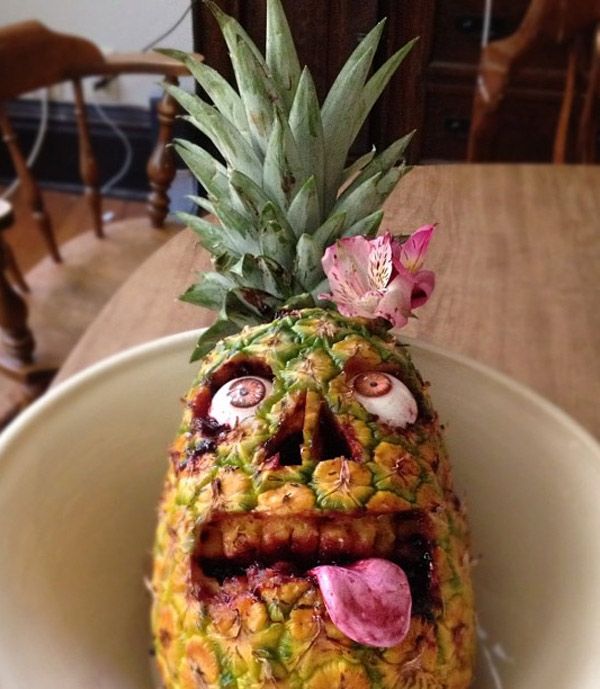 Pineapple carved to look like a zombie face with a laffy taffy candy tonue and jam blood. 