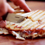 A grilled panini sandwich being sliced in half