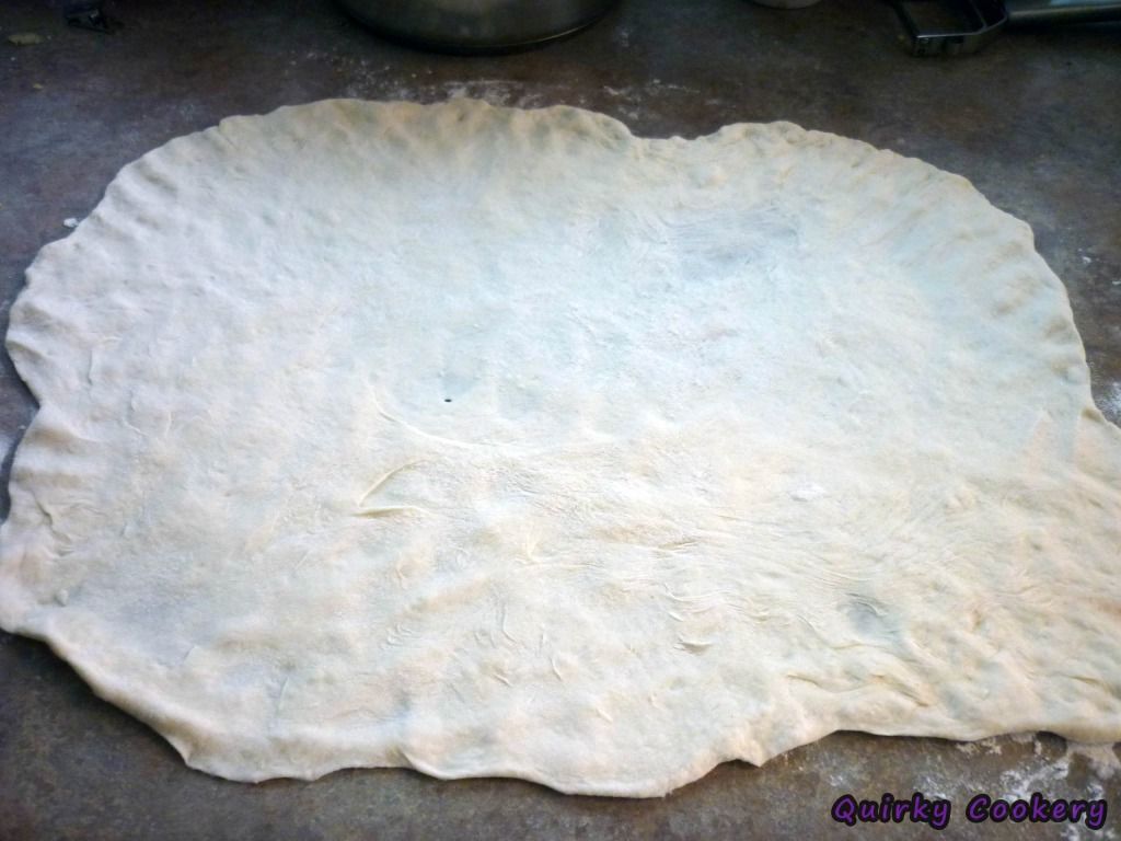 Bread dough that has been flattened out with fingers and rollnig pin to be ready to be filled and rolled