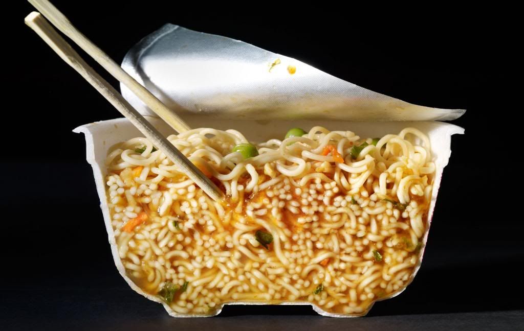 A bowl of ramen noodles and chopsticks cut in half. 