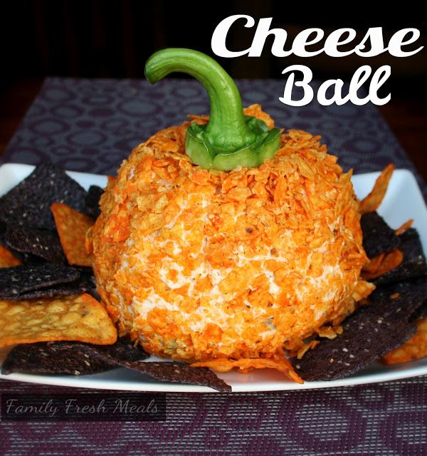 Dorito cheeseball that looks like an orange pumpkin or jackolantern for Halloween with a green bell pepper stem for the top