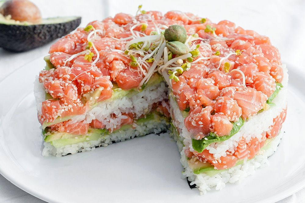 Layered sushi cake with salmon, avocado, cucmber and sesame seeds. Basically it's a California roll or Florida/Seattle roll made into layers to look like a cake instead of sushi rolls. Ice it with wasabi and soy sauce maybe?